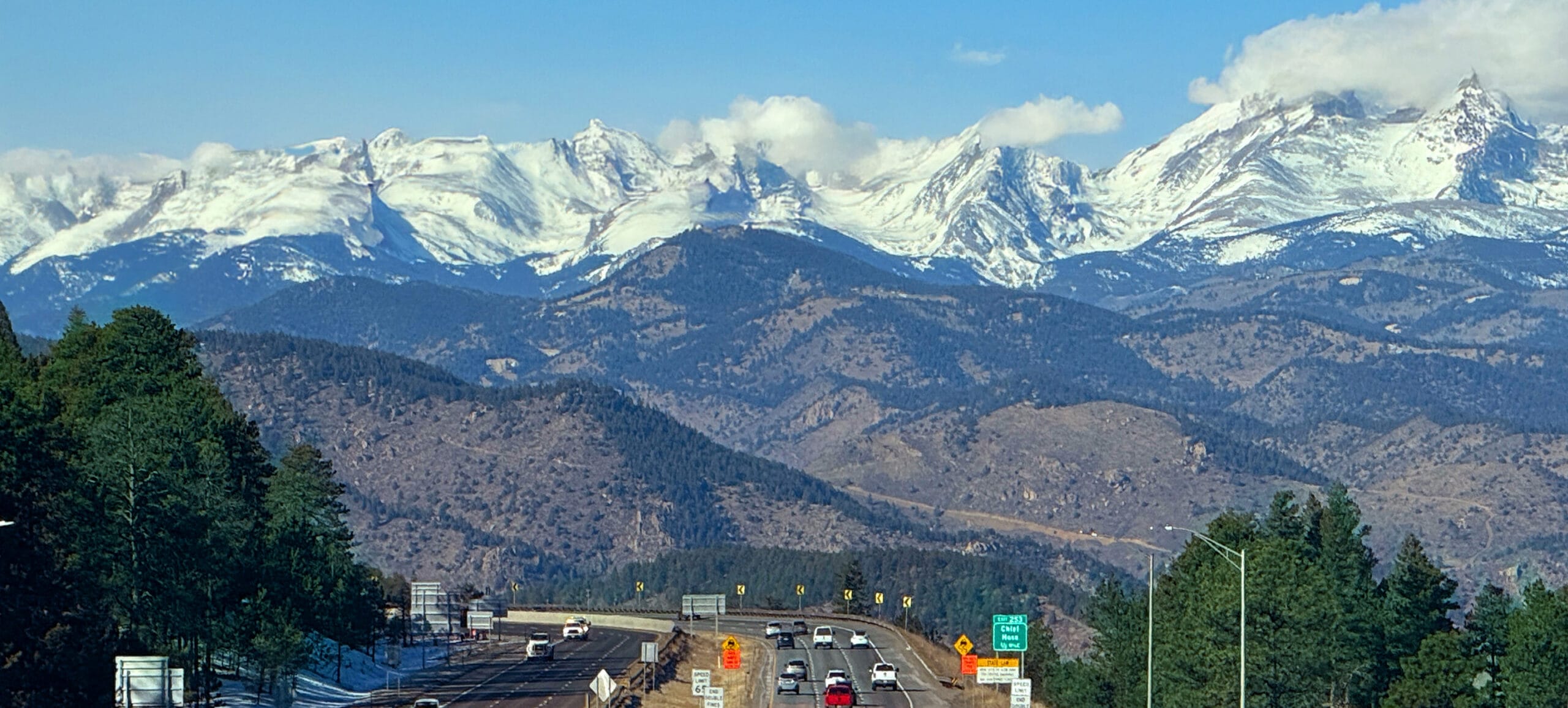 Photo of Colorado mountain range in background with highway in foreground