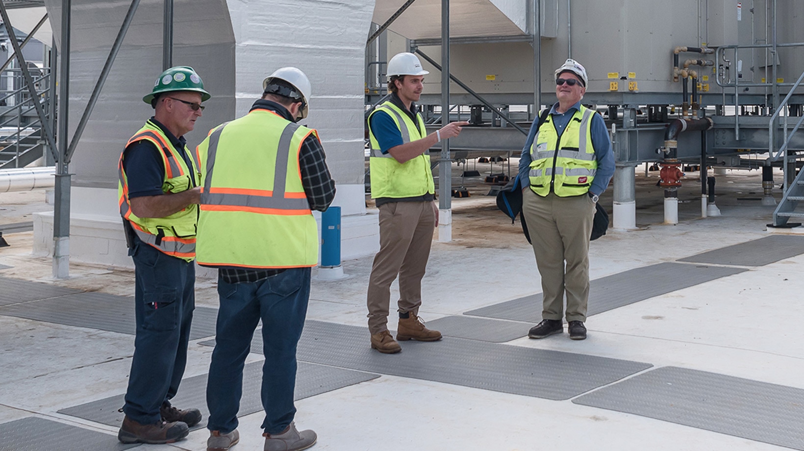 Workers in safety vests and hard hats standing in a group talking