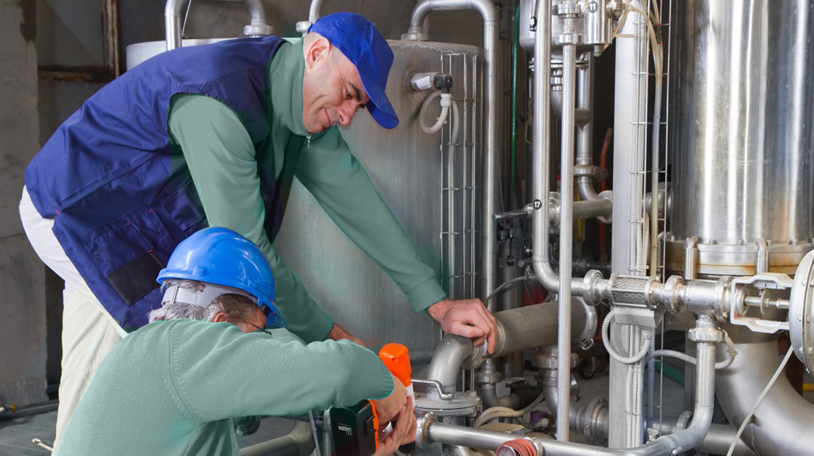 Workers adjusting pipes and valves