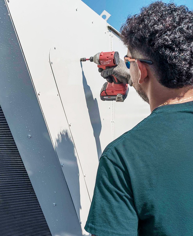 Photo of worker using drill on metal panel